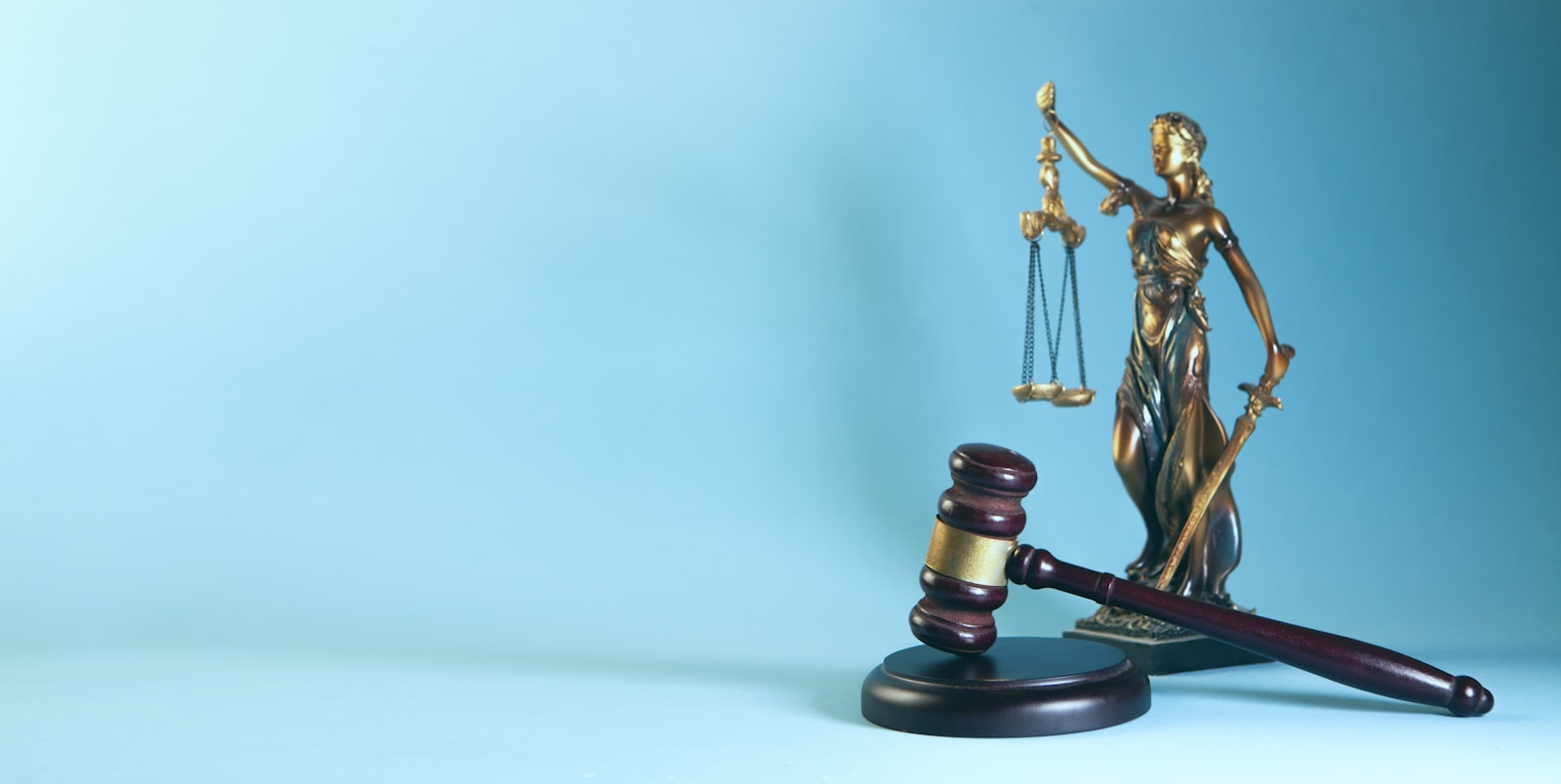 Un marteau de juge et une balance de la justice posés sur fond bleu, symboles d'une procédure judiciaire.