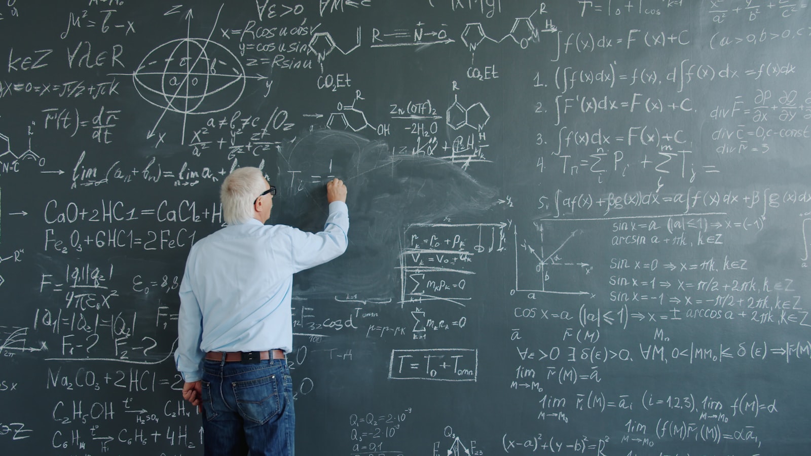 Un professeur de sciences inscrit à la craie des formules mathématiques complexes sur un tableau noir.