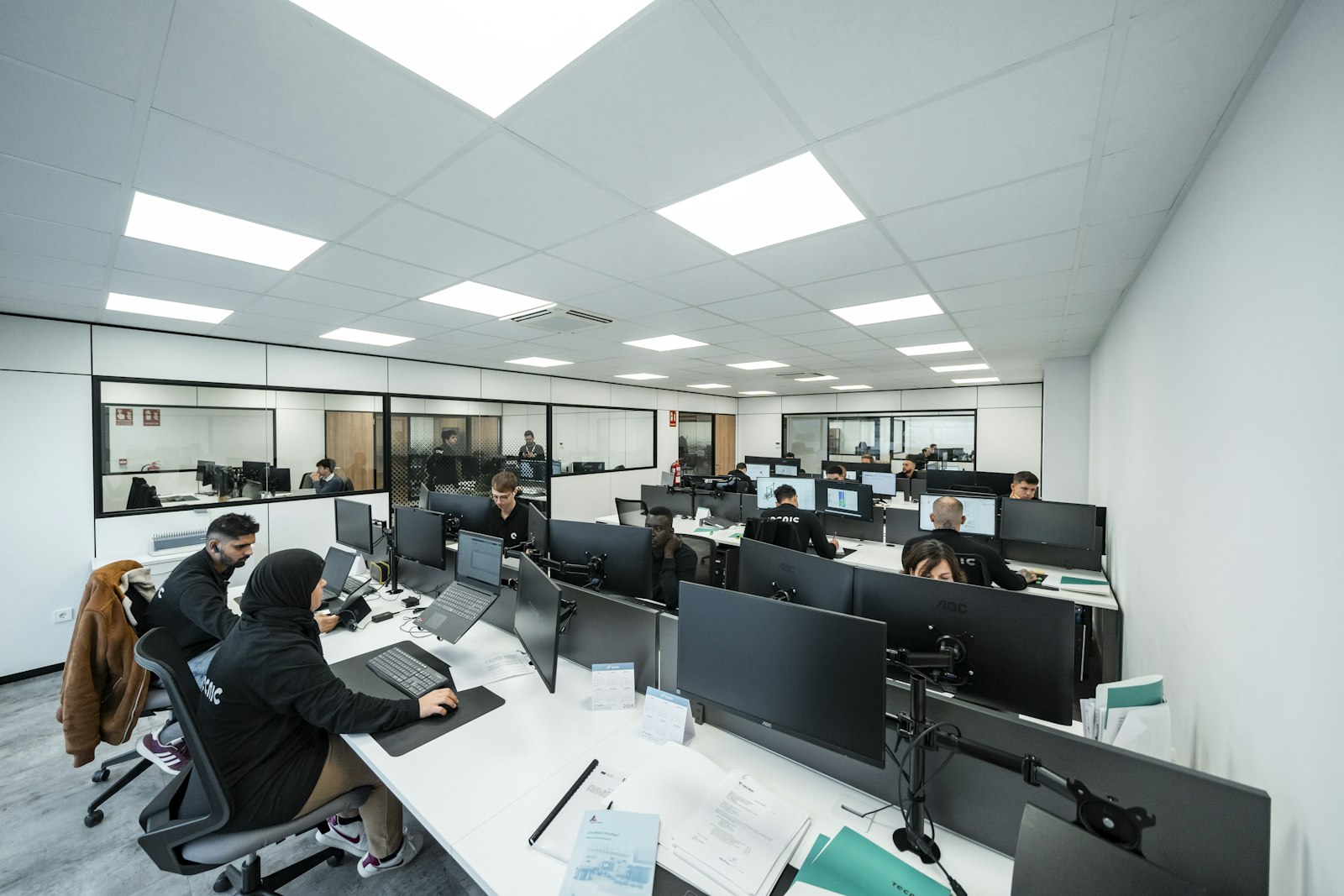 Image d'illustration — bureau en open space, plusieurs employés au travail sur ordinateur