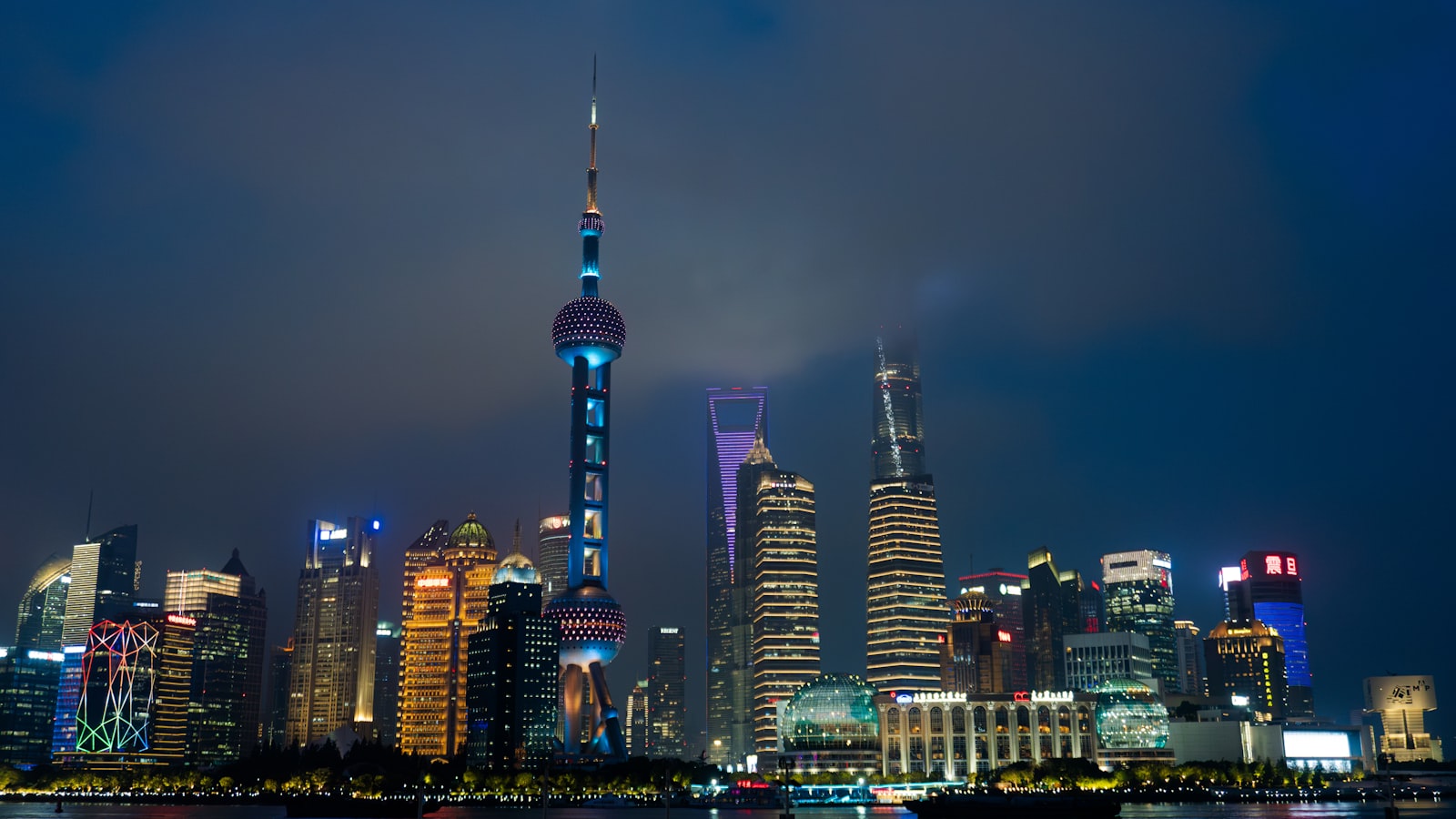 Le skyline illuminé du Bund à Shanghai la nuit, gratte-ciel et tours d'affaires le long du fleuve Huangpu.